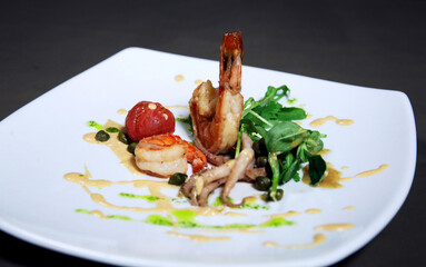 Grilled shrimps or prawns served with greens, garlic and white sauce on a white plate. Seafood....