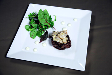 Cooked fillet mignon  with vegetables and sauce on a white plate