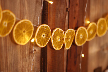 Christmas and New Year background with a garland of dried oranges on a wooden wall.