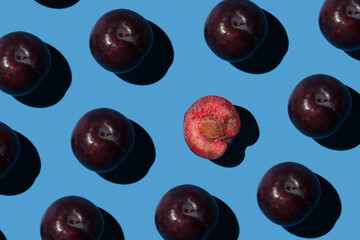 ripe purple pitted plums on blue background