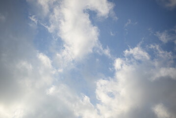 rays of the sun through cirrus clouds against a blue sky, white rainy clouds against a blue sky illuminated by the rays of the sun