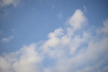 rays of the sun through cirrus clouds against a blue sky, white rainy clouds against a blue sky illuminated by the rays of the sun