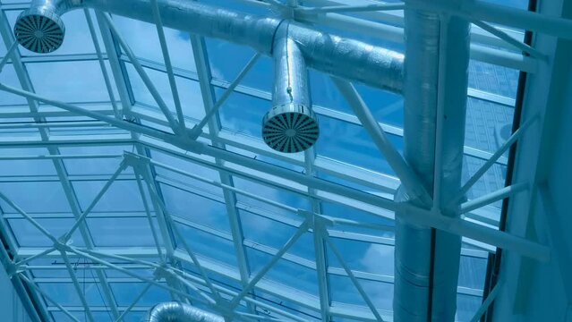 Hangar ceiling with transparent glass roof, many structural beams and ventilation pipes. Shot in motion