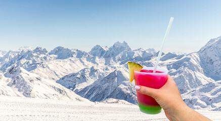 Mountains landscape with Hand holding a glass with cocktail and straw