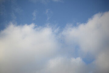 rays of the sun through cirrus clouds against a blue sky, white rainy clouds against a blue sky illuminated by the rays of the sun