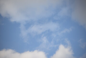 rays of the sun through cirrus clouds against a blue sky, white rainy clouds against a blue sky illuminated by the rays of the sun