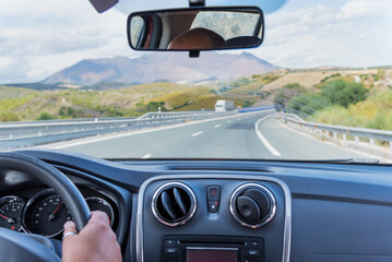 View of the motorway and a landscape of mountains from inside a car driving on the road.