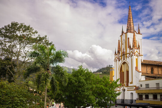 very tall neo-gothic church, white and gold, surrounded by tress