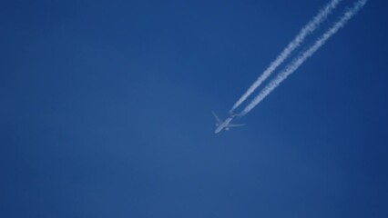 jet plane with contrails at cruising level in blue sky