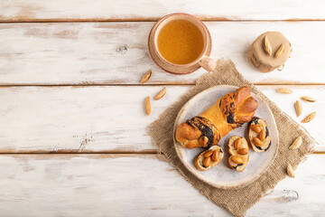 Homemade sweet bun with honey almonds and cup of green tea on a white. top view, copy space.