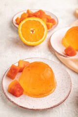 Papaya and orange jelly on gray concrete and orange linen textile. side view.