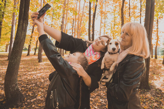 Three generations of women and dog feel fun look at camera posing for self-portrait picture together, funny excited child, mom and grandmother have fun enjoy weekend take selfie on gadget in autumn