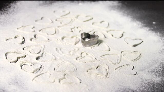 the hearts are taken out of the cookie baking dish and spread on a floured surface and sprinkled with flour on top like snow. culinary layout