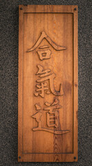 The inscription "uli" probably because of Chinese on a wooden board / Gray rough wall in the background