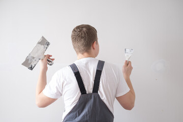 A man holds a trowel in his hands and plans to level the walls of the house