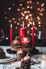 Rustic table decor for Christmas or New Year family dinner. Centrepiece with red candle, dry orange, cone, cinnamon, anise. Zero waste eco-friendly home. Cozy atmosphere, dark background. Close up