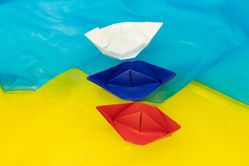 The flag of Russia from paper boats float on the water on the flags of Ukraine, the war in Ukraine with Russia