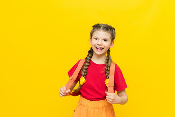 A schoolgirl with a satchel is getting ready to go to school. Children's education. Preparatory courses for schoolchildren. Additional classes for successful exams. Yellow isolated background.