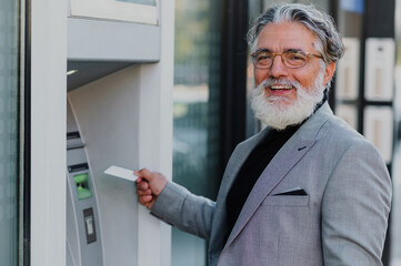 Senior business man using atm machine and credit or debit card