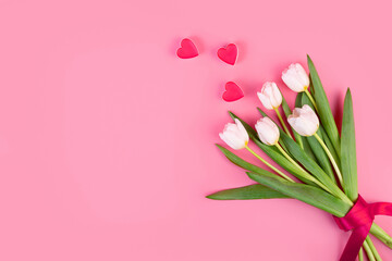 White tulips flowers with hearts. Beautiful bouquet of tulips on stem with leaves isolated on pastel pink background. Naturе object for design to women's day, mother's day, anniversary. Spring concept