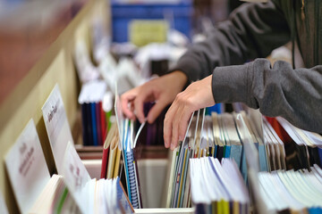 Selective focus of teen hands choosing music textbook at bookstore. 