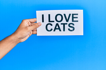 Hand of caucasian man holding paper with i love cats message over isolated blue background
