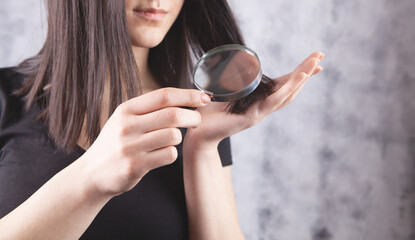 young girl examines her hair with a magnifying glass. hair problem concept