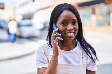 Young african american woman smiling confident talking on the smartphone at street