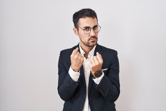 Handsome business hispanic man standing over white background ready to fight with fist defense gesture, angry and upset face, afraid of problem