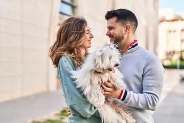 Man and woman holding dog hugging each other at street