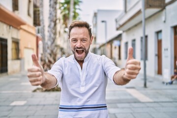 Middle age man outdoor at the city approving doing positive gesture with hand, thumbs up smiling...