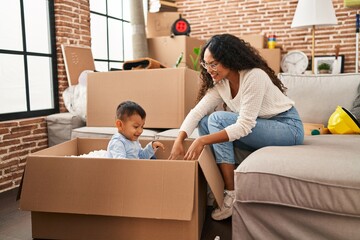 Mother and son playing with cardboard as a car at new home