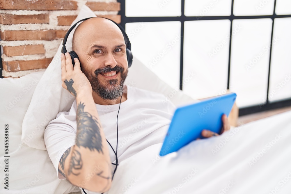 Canvas Prints Young bald man watching video on touchpad on bed at bedroom