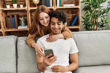 Young couple smiling happy and hugging sitting on the sofa at home.