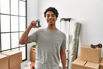 Young hispanic man smiling happy holding inhaler at new home.
