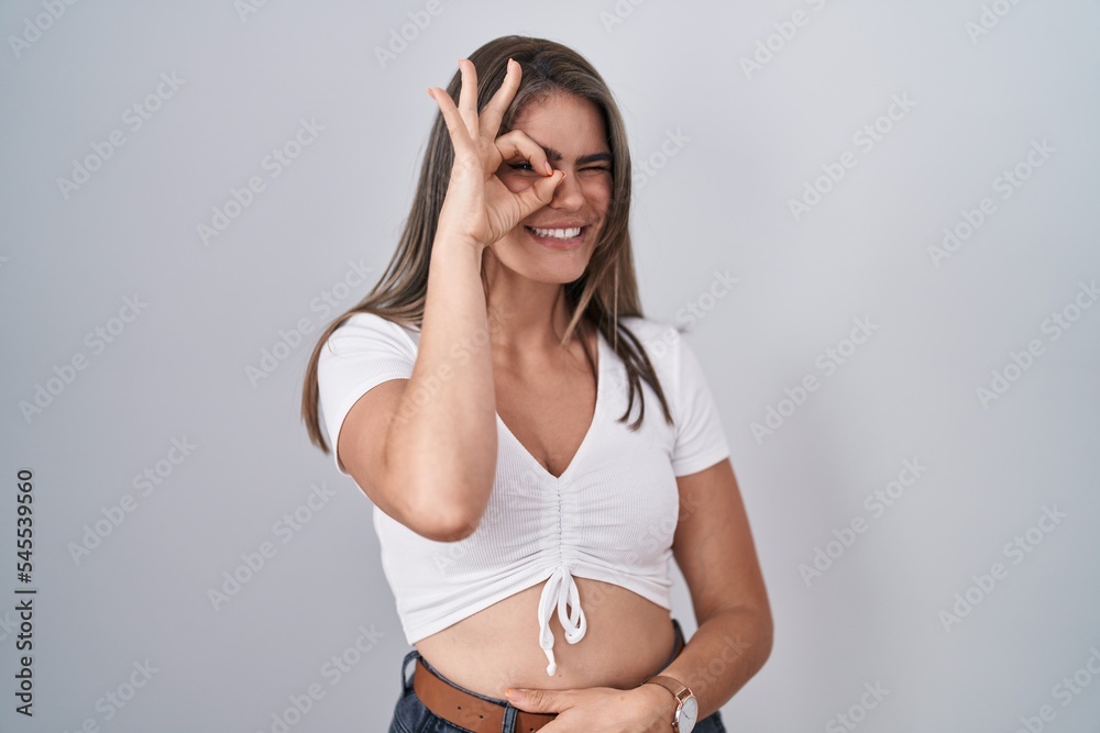 Sticker young beautiful woman wearing casual white t shirt doing ok gesture with hand smiling, eye looking t