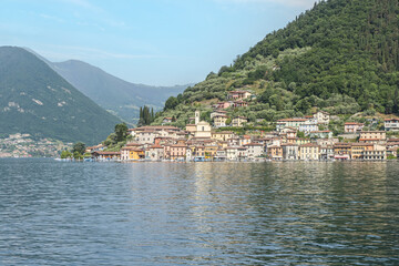Fototapeta na wymiar Landscape of the lakeside of Peshiera Maraglio in Monte Isola with beautiful colored houses reflecting in the water