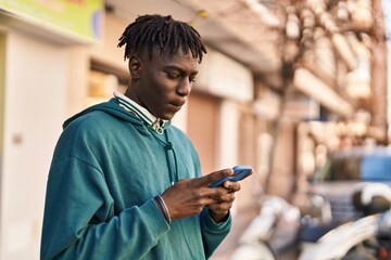 Fototapeta na wymiar African american man smiling confident using smartphone at street