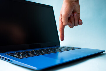 Fototapeta na wymiar Hand touching a blue laptop on blue background 