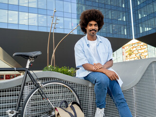 Young african american man with afro hair in a financial district with a bicycle. Young entrepreneur