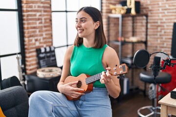 Fototapeta na wymiar Young hispanic woman musician playing ukelele at music studio