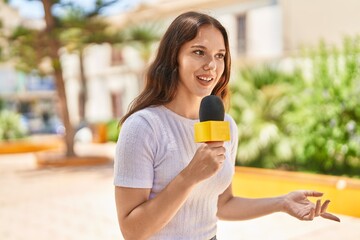 Young woman reporter working using microphone at park