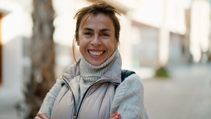 Middle age hispanic woman smiling confident standing with arms crossed gesture at street