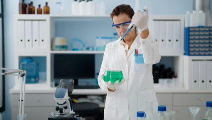 Middle age hispanic woman wearing scientist uniform working at laboratory