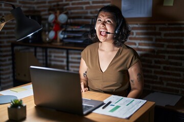 Young hispanic woman working at the office at night angry and mad screaming frustrated and furious, shouting with anger. rage and aggressive concept.