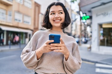 Young woman smiling confident using smartphone at street