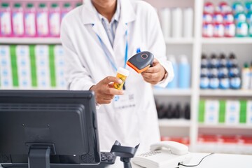 Young beautiful hispanic woman pharmacist scanning pills bottle at pharmacy