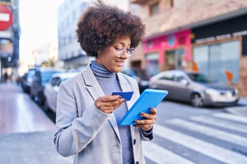 African american woman executive using touchpad and credit card at street