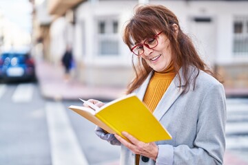 Middle age woman business executive reading book at street