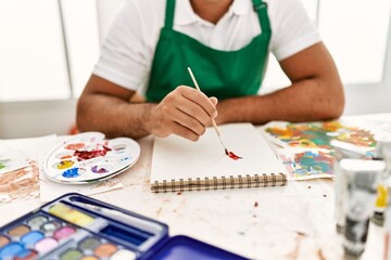 Fototapeta na wymiar Young hispanic man drawing on notebook at art studio
